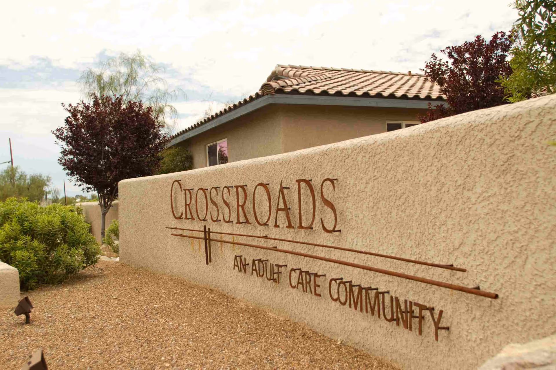 Exterior view of Crossroads adult care community with a large sign on a textured front wall.