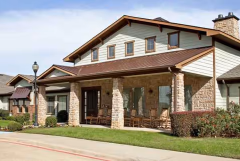 Front view of Magnolia Court Assisted Living Memory Care building with stone columns and porch seating.