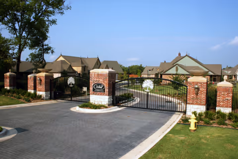 Gated brick entrance to a senior living campus with decorative pillars and manicured landscaping.
