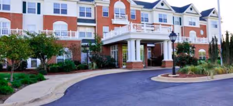 Red-brick senior living building with a covered entrance and curved driveway.