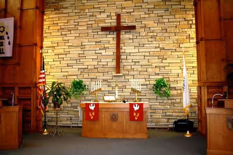 Interior chapel at The Lutheran Home: Belle Plaine, featuring altar, cross, candles, flags, and plants.
