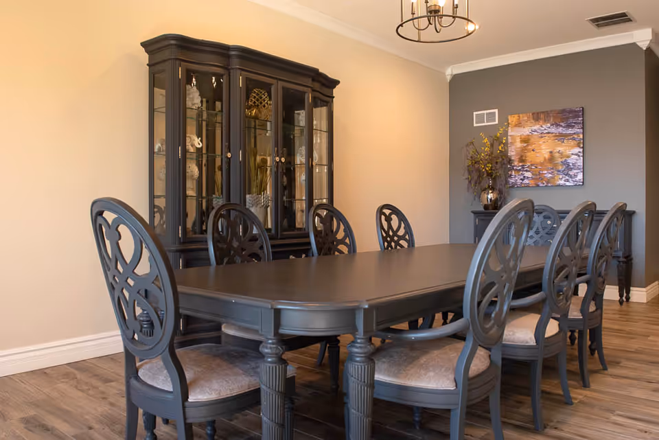 Formal dining room with a long dark wood table, ornate chairs, and a glass-front china cabinet.