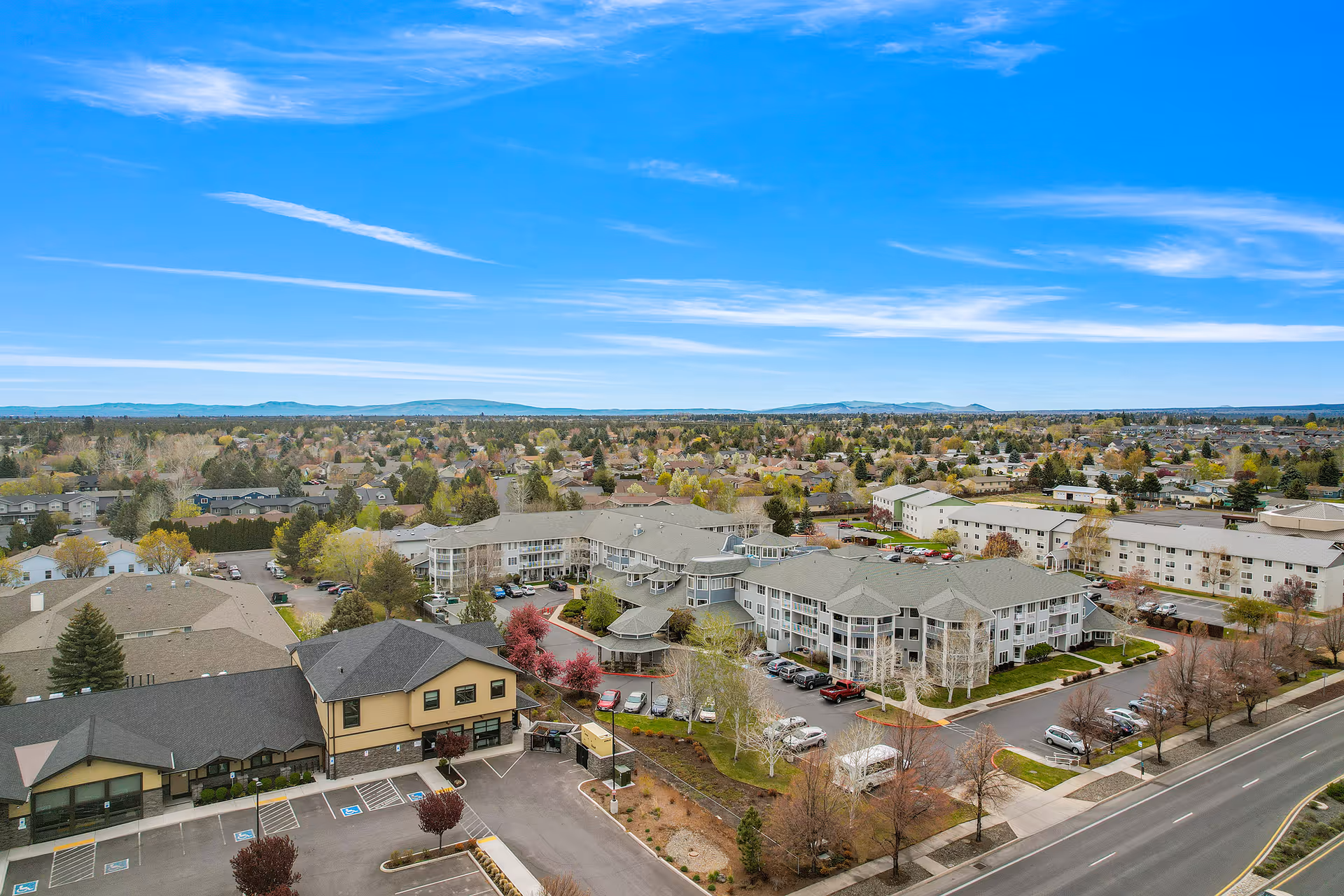 Aerial view of Stone Lodge retirement living complex with multiple beige buildings, parking, and surrounding streets.