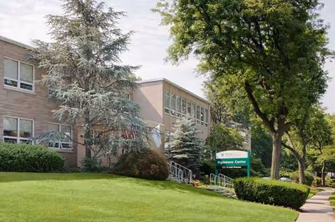 Exterior view of Complete Care at Inglemoor facility with trees and green lawn.