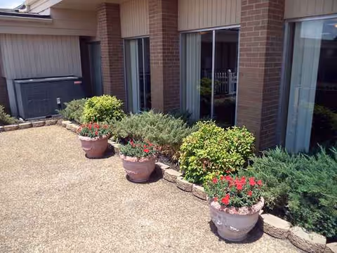 Exterior view of Sweetwater Nursing Center with potted plants along walkway.