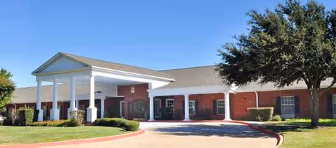 Brick senior living facility with a white portico entrance and manicured landscaping.