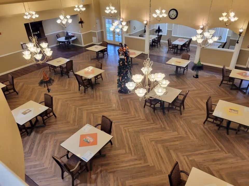 Overhead view of a spacious dining room with multiple square tables, chandeliers, and a decorated central tree.