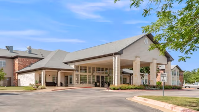 Front entrance of Brookdale Round Rock with a covered porte-cochere, driveway, and landscaped grounds.