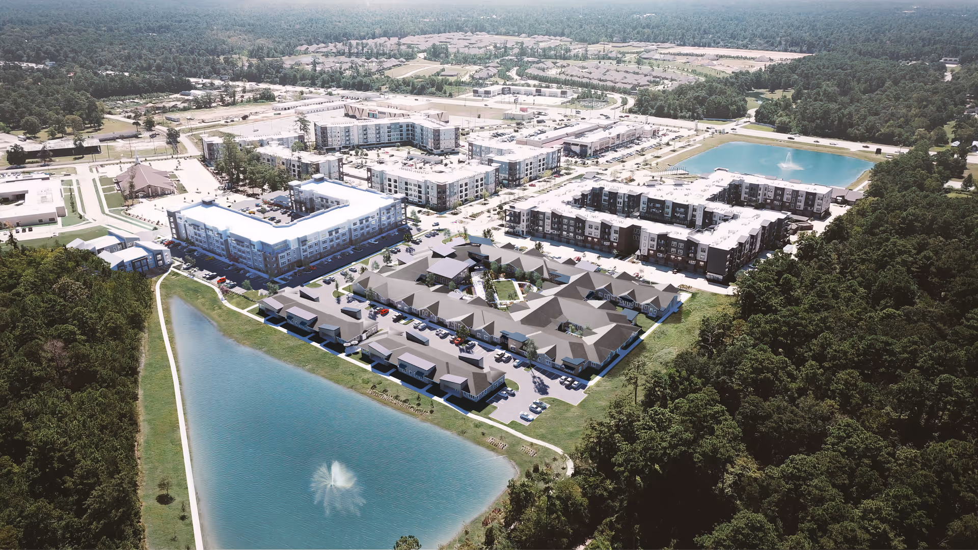 Aerial view of The Reserve at Woodland Lakes senior living facility showing multiple buildings arranged around a large pond with a fountain, surrounded by trees and greenery, with parking lots and roads visible.