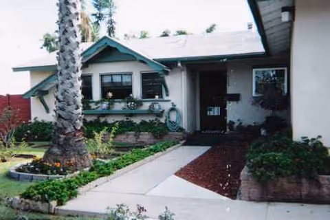 Single-story facility front entrance with a walkway and landscaped garden beds.