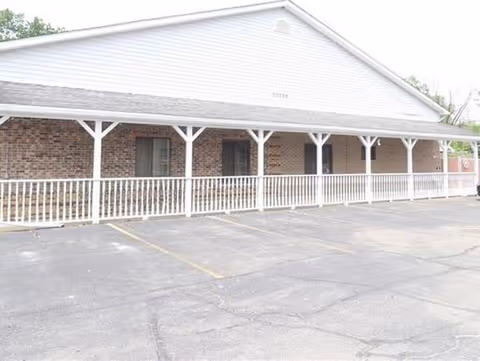 Exterior view of Sumpter Senior Living with a brick facade and white porch railing.
