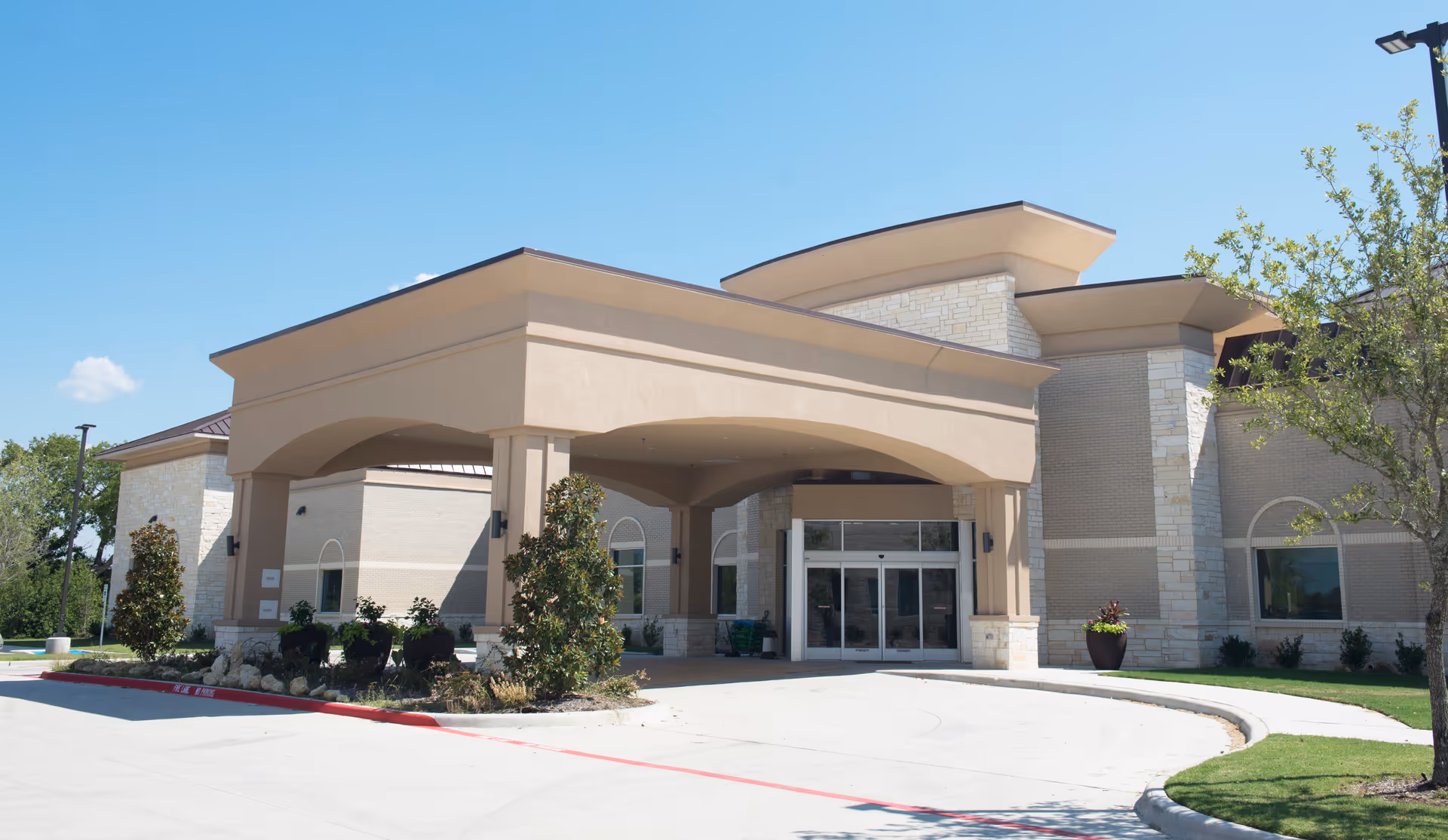 Exterior view of Highlands Village Senior Living entrance with curved entry canopy.