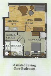 Floor plan of an assisted living one-bedroom unit showing a kitchenette, living room with furniture, bedroom with a bed and desk, walk-in closet, and bathroom with a shower, toilet, and sink.