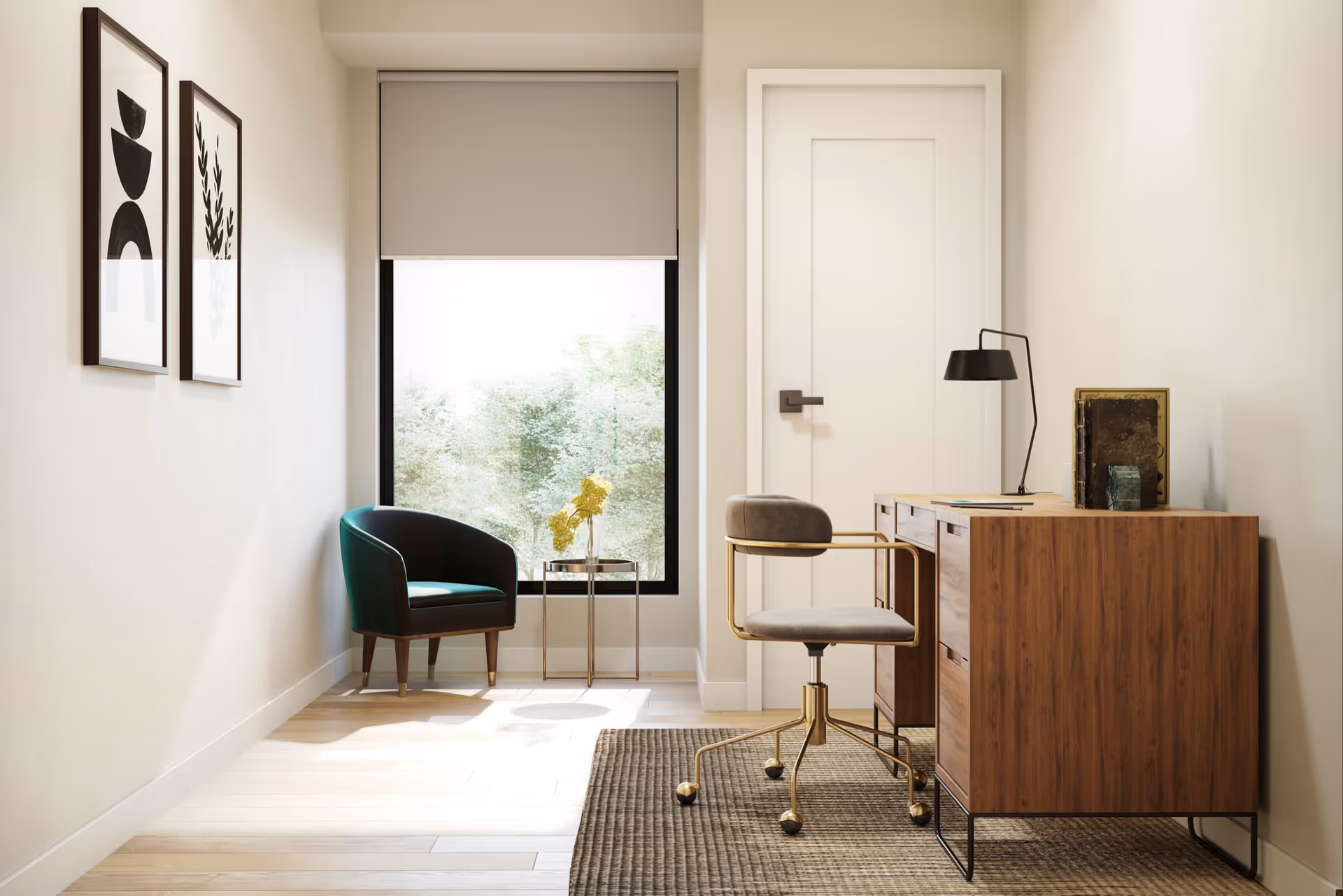 A bright, minimalist interior room featuring a wooden desk with a modern gray and gold office chair on a textured rug. To the left, there is a small round side table with a vase of yellow flowers and a dark green armchair near a large window with a beige roller shade. Two framed abstract black and white artworks hang on the left wall.