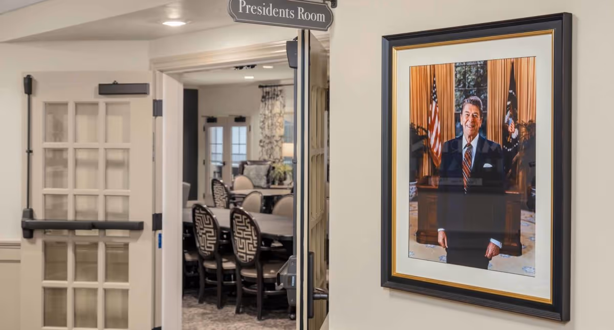 Open doorway labeled 'Presidents Room' revealing a dining/meeting table with chairs and a framed portrait on the wall.