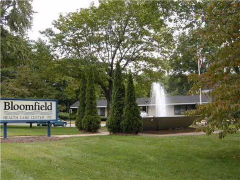 Exterior view of Bloomfield Health Care Center with fountain and landscaped front lawn.