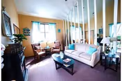 Light-filled senior living lounge with sofa, chairs, coffee table, and decorative divider.