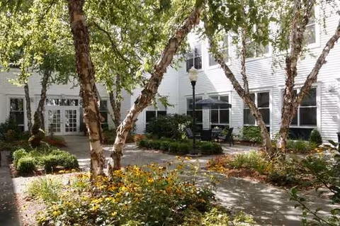 Exterior of Wingate at Sudbury with trees, shrubs, and outdoor seating.