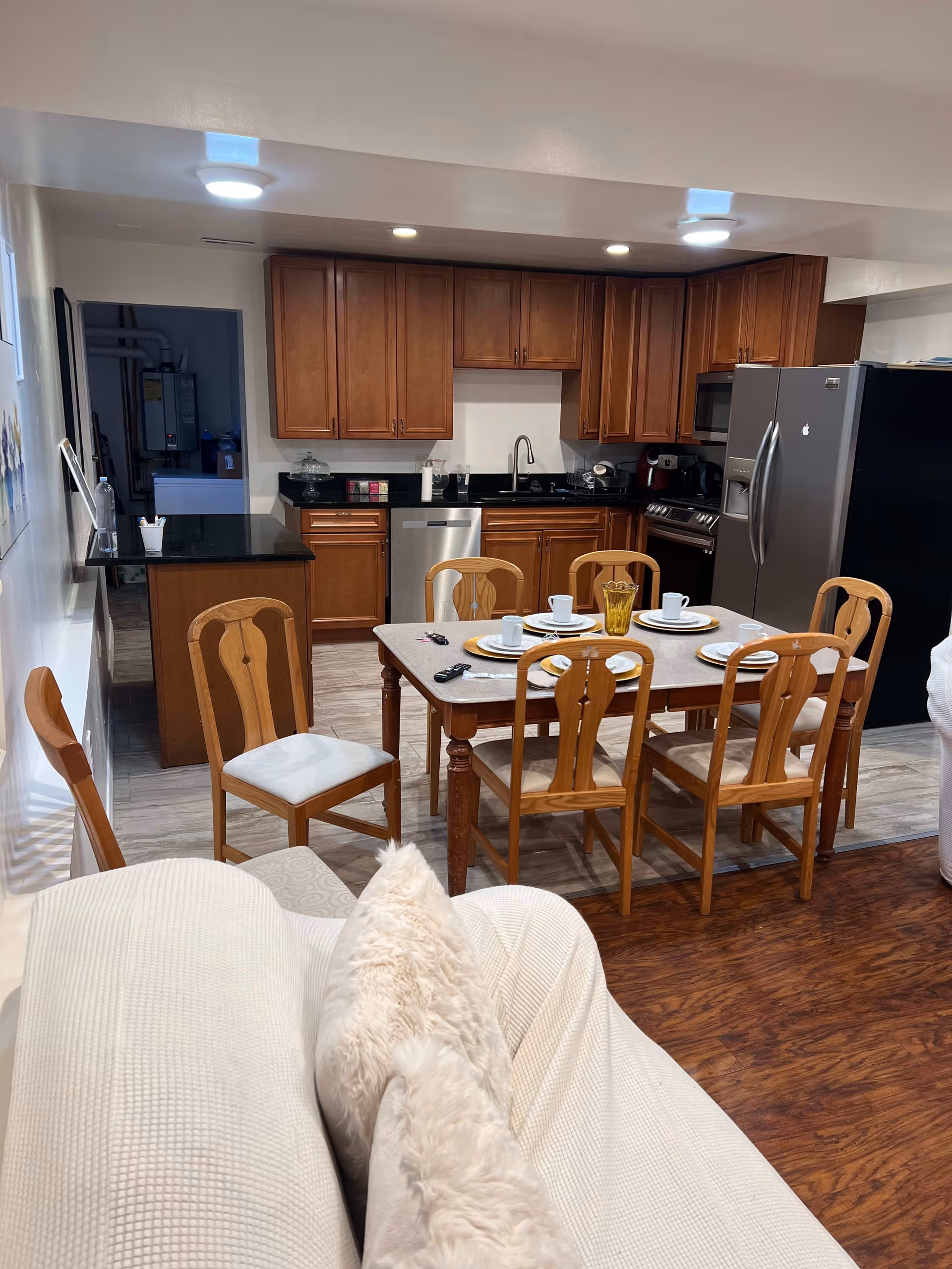 Open-plan kitchen and dining area with wooden cabinets, stainless steel appliances, and a set table with six wooden chairs.