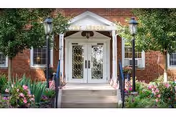 St. Barnabas entrance with brick facade, white double doors, lamps, and landscaped surroundings.