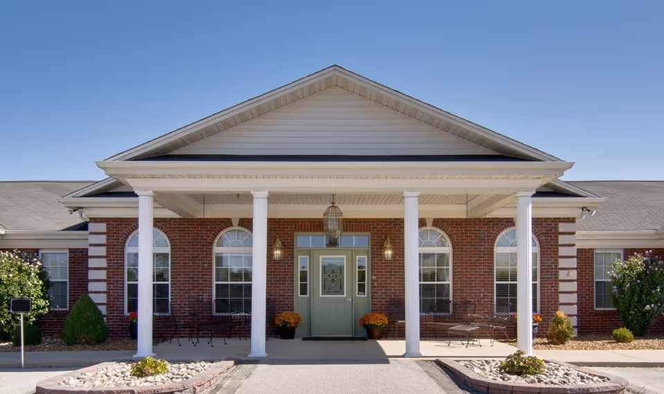 Front exterior of Teal Lake Senior Living, brick building with columns and a peaked roof.