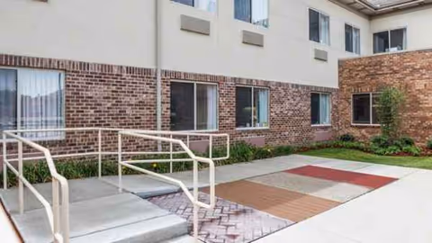 Exterior view of Monroeville Skilled Nursing and Rehabilitation Center with brick facade and courtyard pathway.