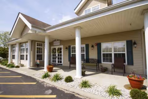 Front entrance of a senior living facility with a covered porch and benches.