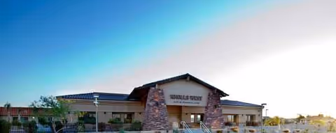 Wide view of Knolls West Residential Care building exterior with stone entry and clear sky.