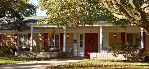 Front view of Golden Gardens exterior with porch, trees, and two entry doors.