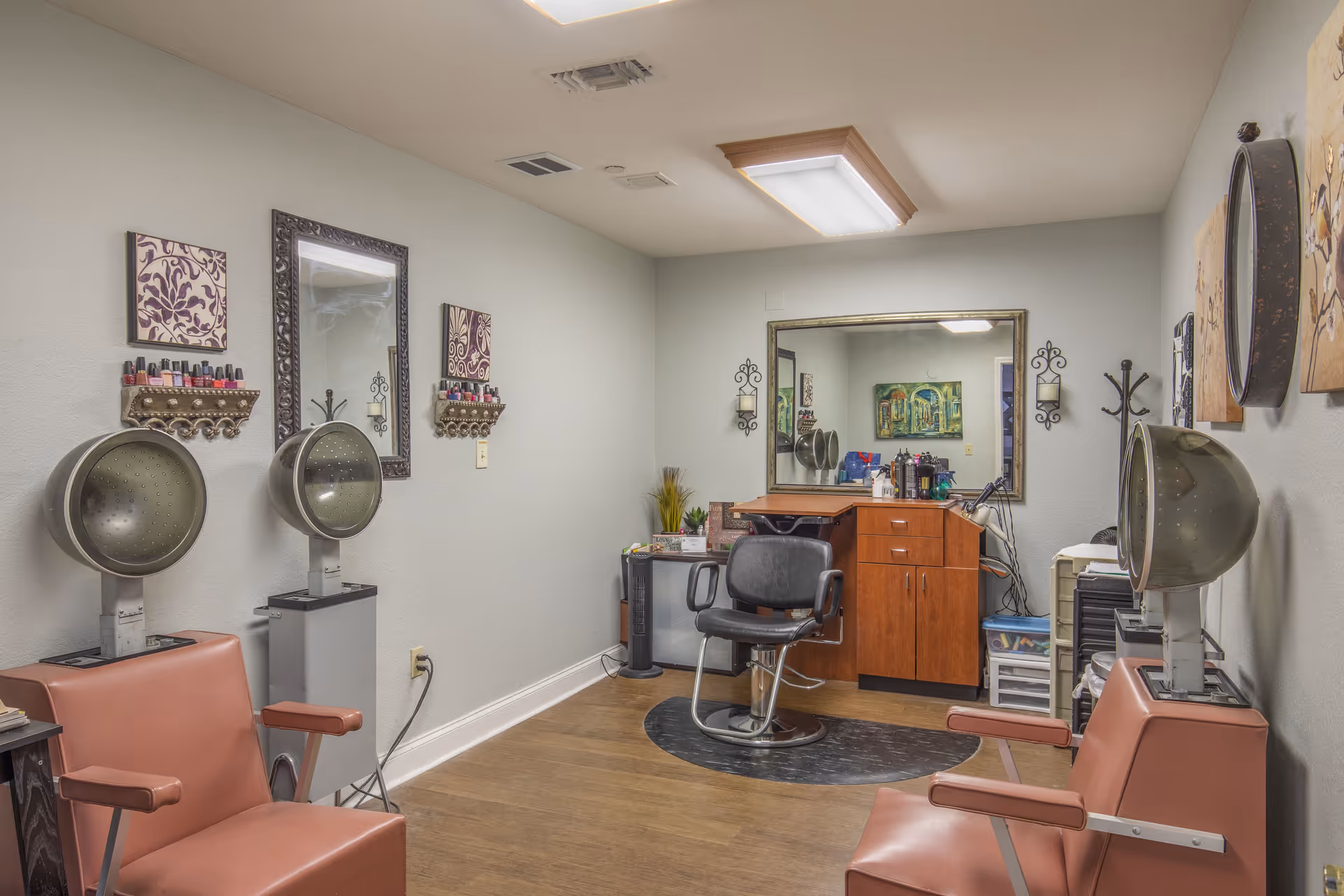 Interior salon room with hair dryers, styling chairs, mirrors and a styling station.