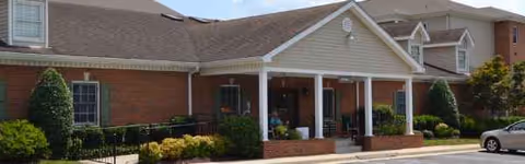 Brick senior living facility with a covered porch and landscaped entrance.