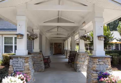 Covered entrance to Sunrise of Richmond senior living facility with stone columns and hanging baskets.