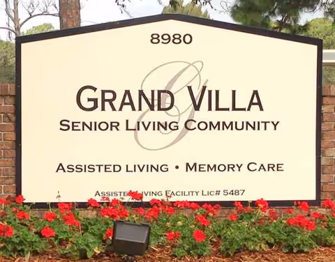 Front view of Grand Villa Senior Living Community sign with flowers