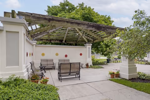 Outdoor courtyard with benches under a weathered pergola at Brookdale Des Plaines.