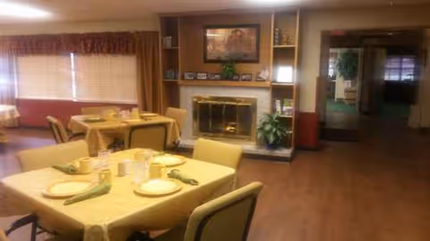 Senior living dining room with set tables and a fireplace.