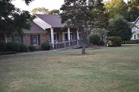 A single-story senior living facility with a ramped entrance and grassy front yard.