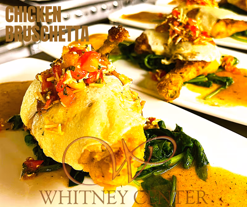 Close-up of plated chicken bruschetta served on a bed of cooked spinach with sauce on the side, with multiple plates arranged in a row.