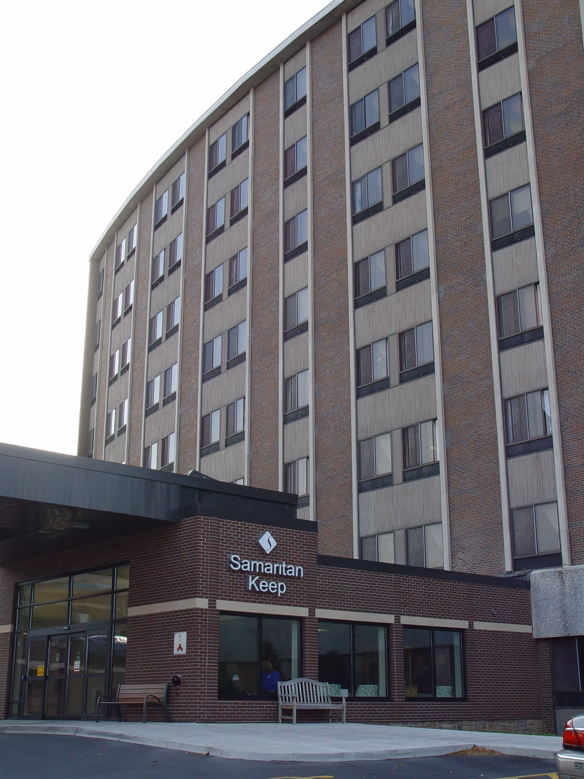 Exterior front view of a multi-story brick senior living building with a canopy entrance and a sign reading 'Samaritan Keep'.