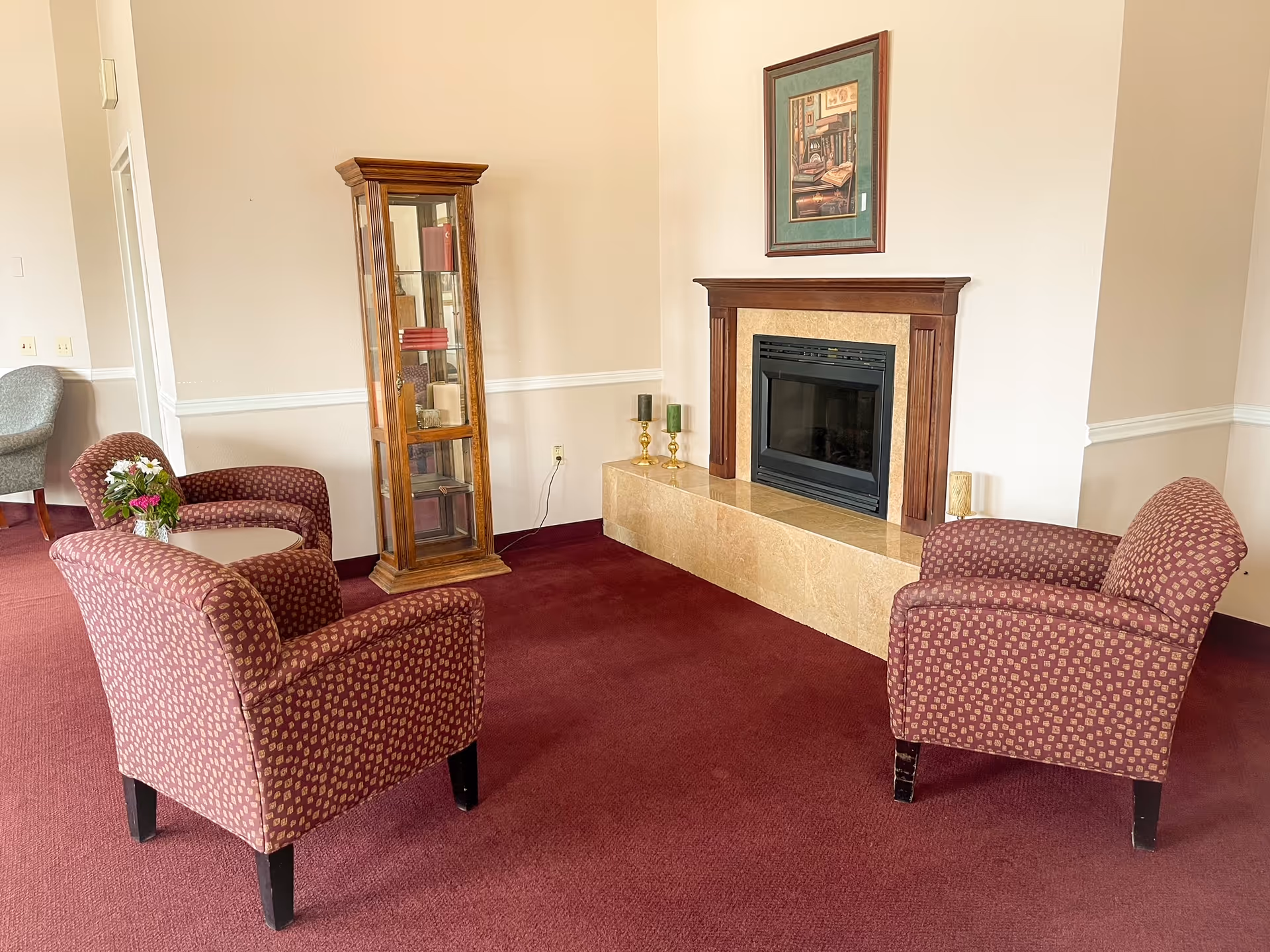 Cozy lounge area with two patterned chairs and a fireplace.