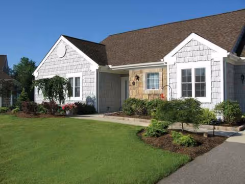 White-shingled Laurel Lake Retirement Community building with manicured lawn and stone entry.