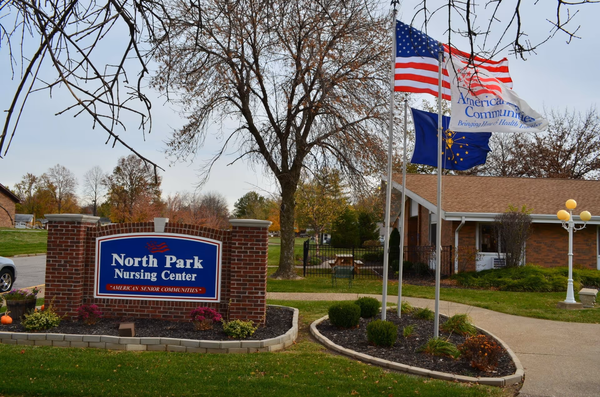 Brick sign reading "North Park Nursing Center" in front of a single-story brick building with flagpoles and landscaping.
