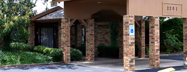 Covered brick entrance with pillars, landscaping, a handicapped parking sign, and the address "2201".