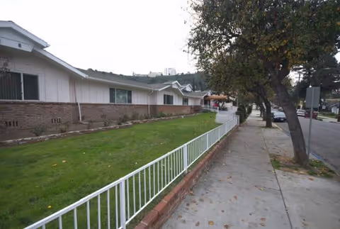 Side exterior view of Glen Park at Glendale Boynton with lawn, white railing, and sidewalk.