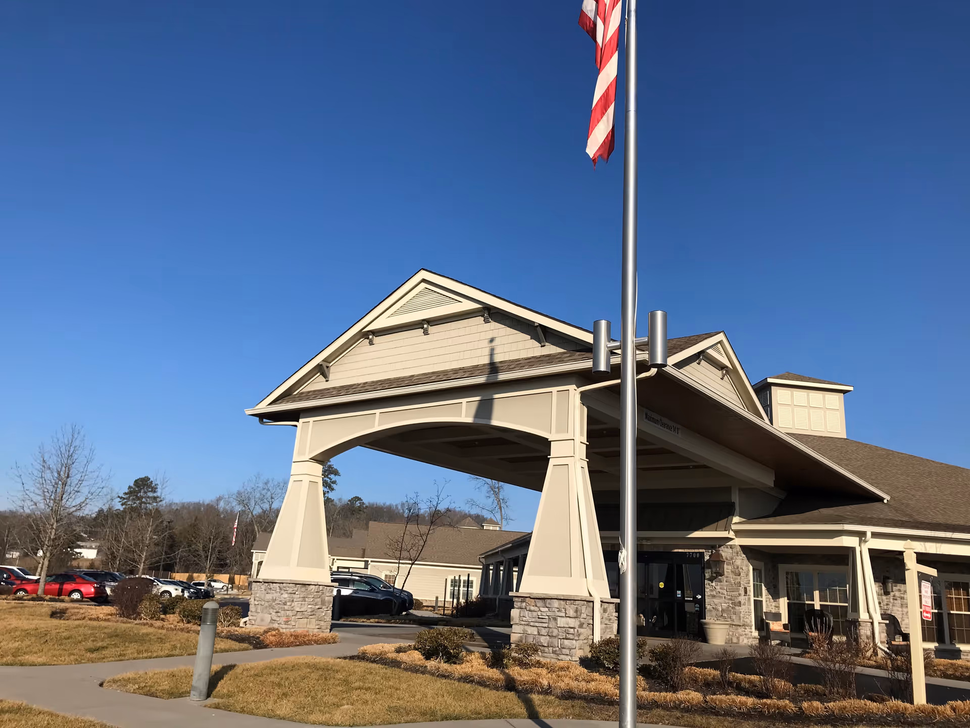 Front entrance of Morning Pointe of Powell with a porte-cochere and flagpole against a clear blue sky.