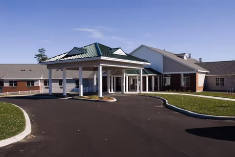 Pine Harbour senior living facility entrance with a covered drop-off area and circular driveway.