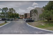 Exterior view of a multi-story assisted living building with a parking lot.