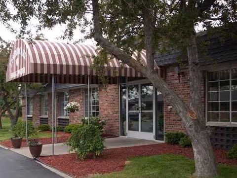 Exterior view of a brick senior living facility entrance with a striped awning.