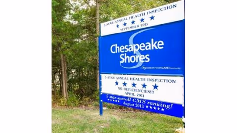 Outdoor sign for Chesapeake Shores Nursing Center displaying 5-star annual health inspection ratings from various years, surrounded by trees and grass.