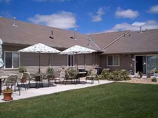 Backyard patio of Prairie Pines Lodge with tables, chairs, and umbrellas along the building.