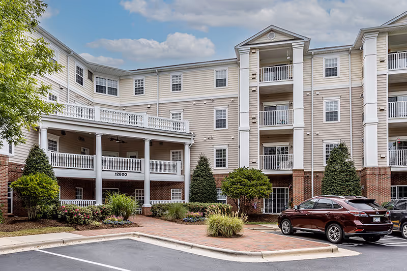 Exterior view of Gardens at Wakefield with balconies and parked cars.